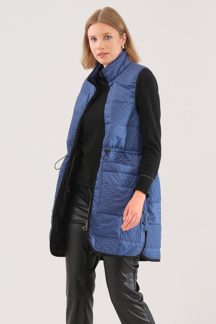 Woman wearing a blue puffer vest over a black outfit on a white background