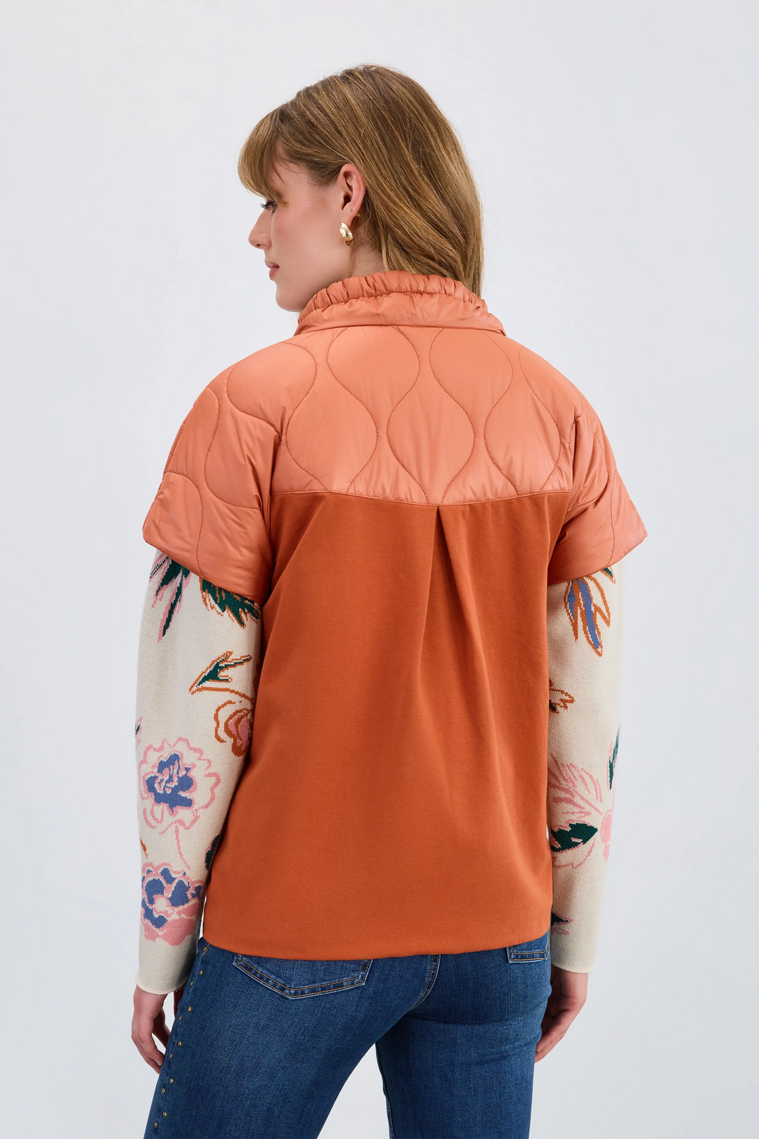 Woman wearing a two-tone jacket with orange and pink sections on a white background