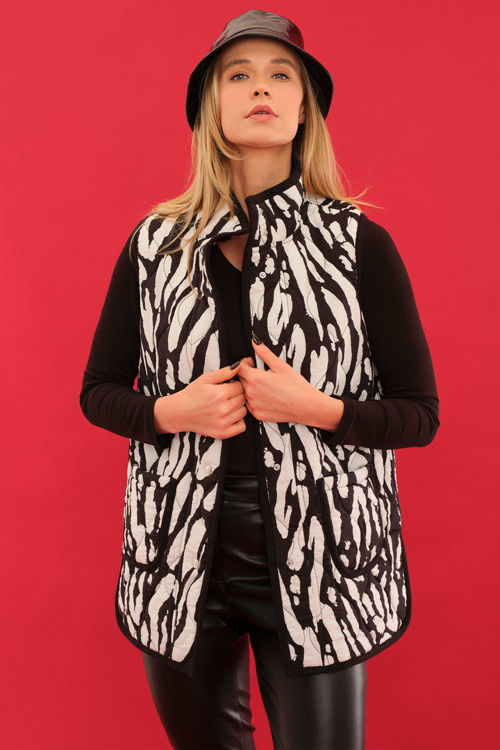 Person wearing a black and white patterned vest over a black shirt on a red background