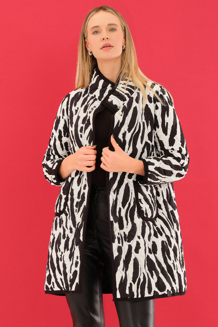 Woman wearing a black and white patterned coat against a red background