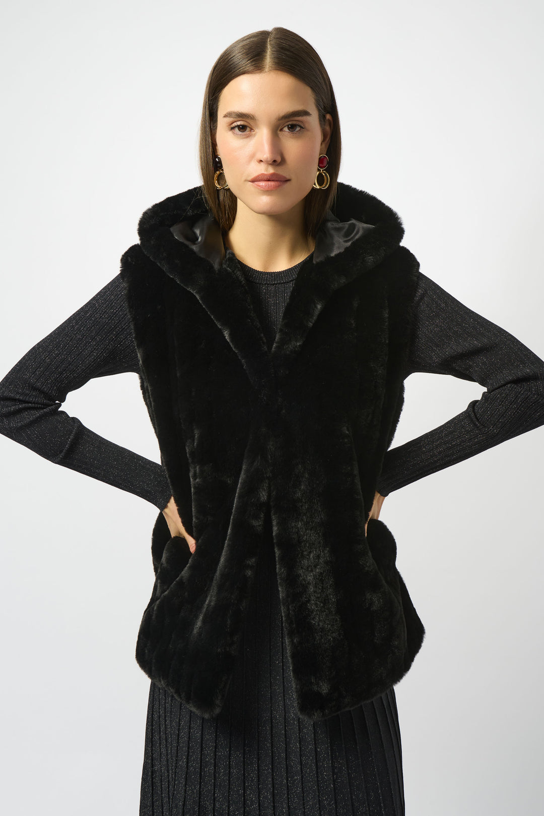 Woman wearing a black fur vest over a gray sweater on a white background