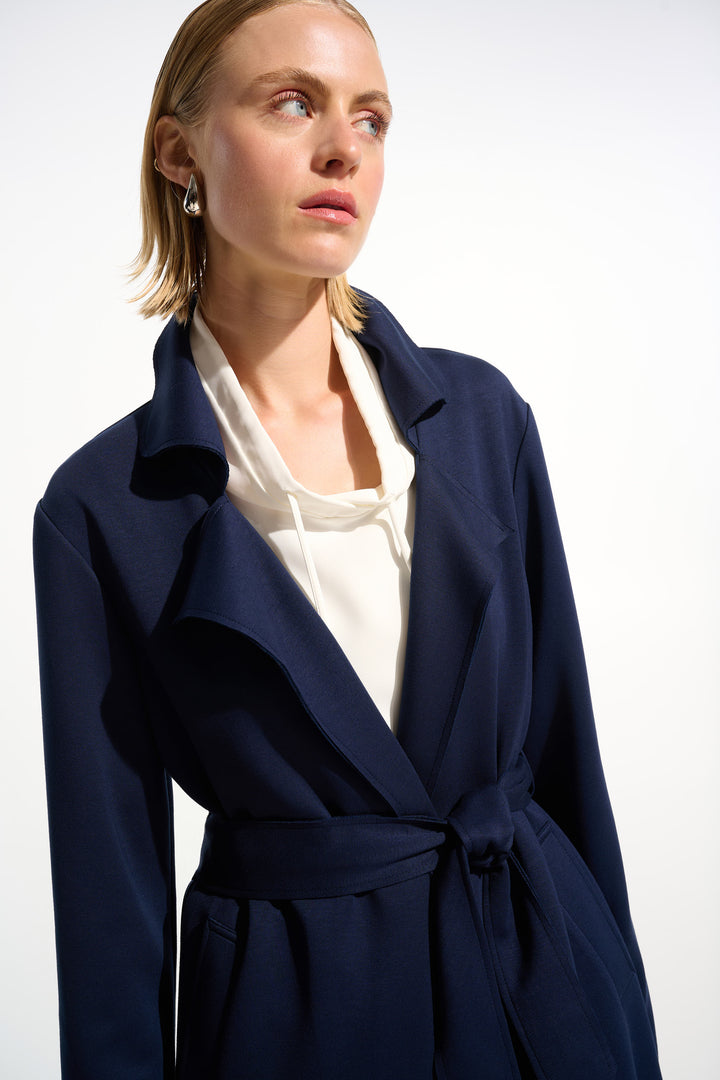 Woman wearing a navy blue coat over a white shirt on a white background