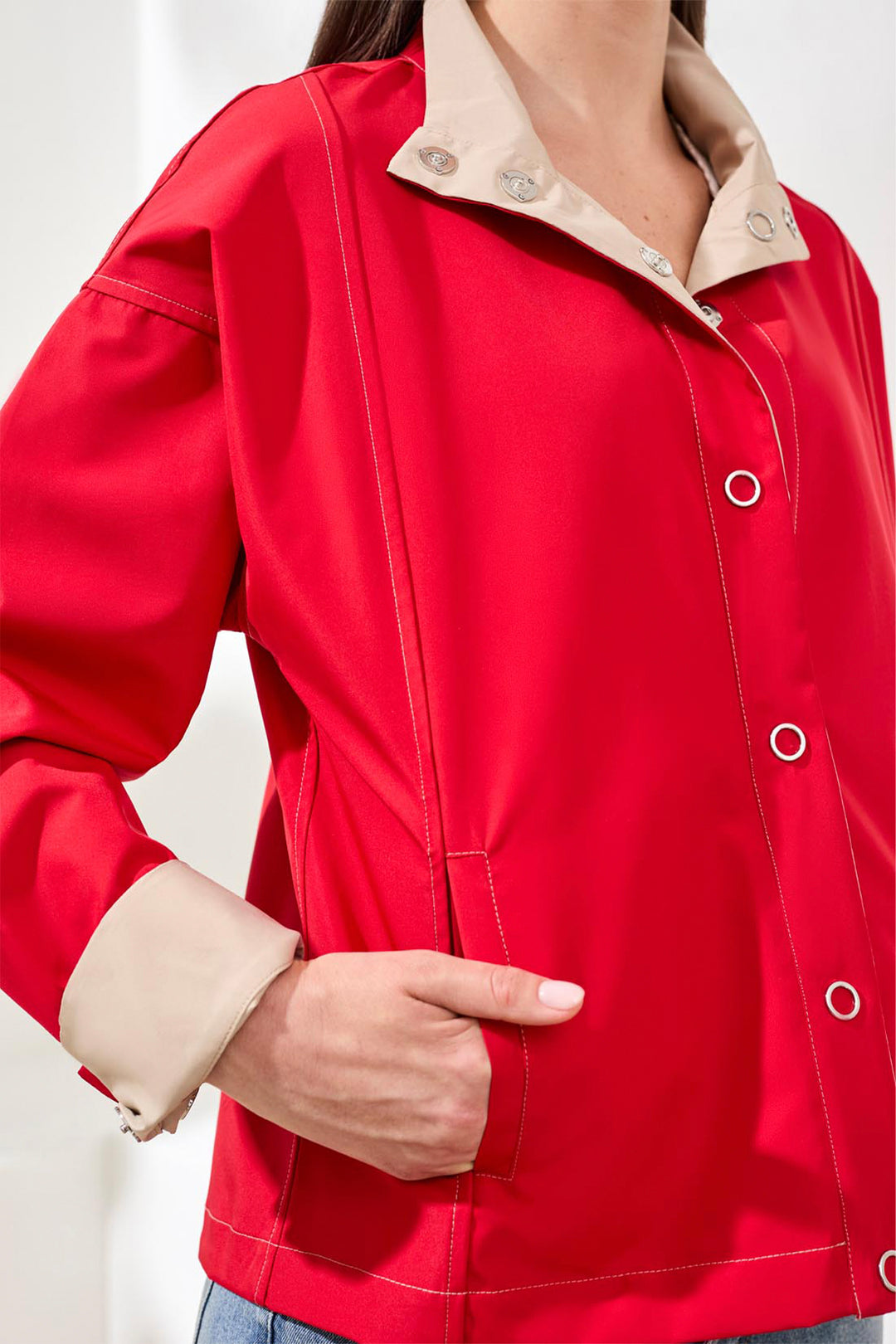 Red rain jacket with beige collar and buttons on a white background