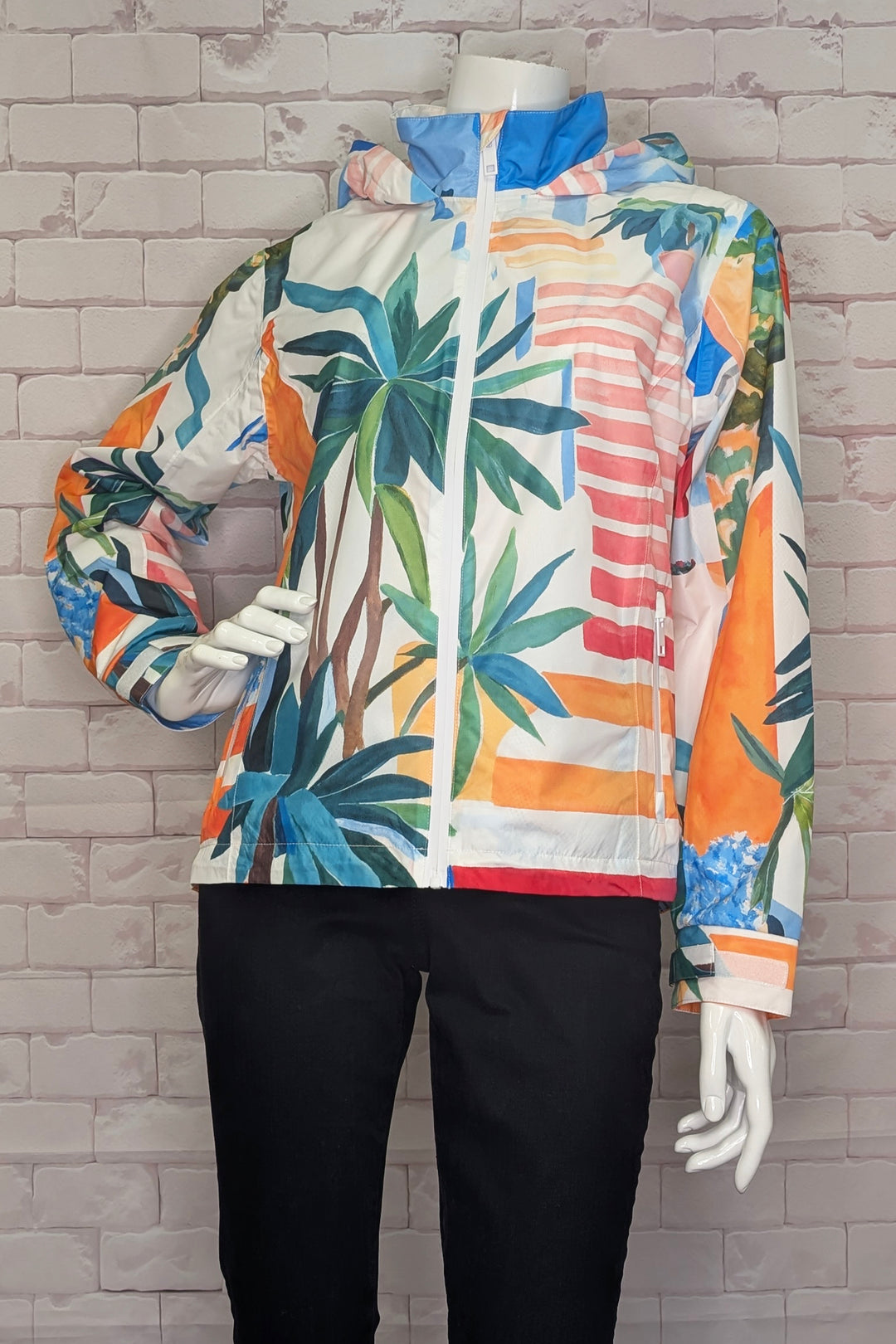 Colorful jacket with palm tree design on a mannequin against a brick wall.