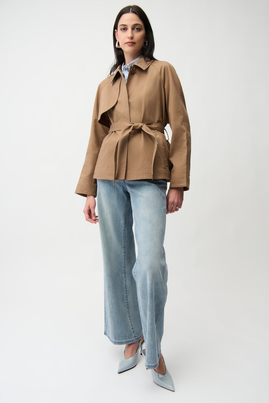 A woman modelling a short brown trench coat and jeans. 