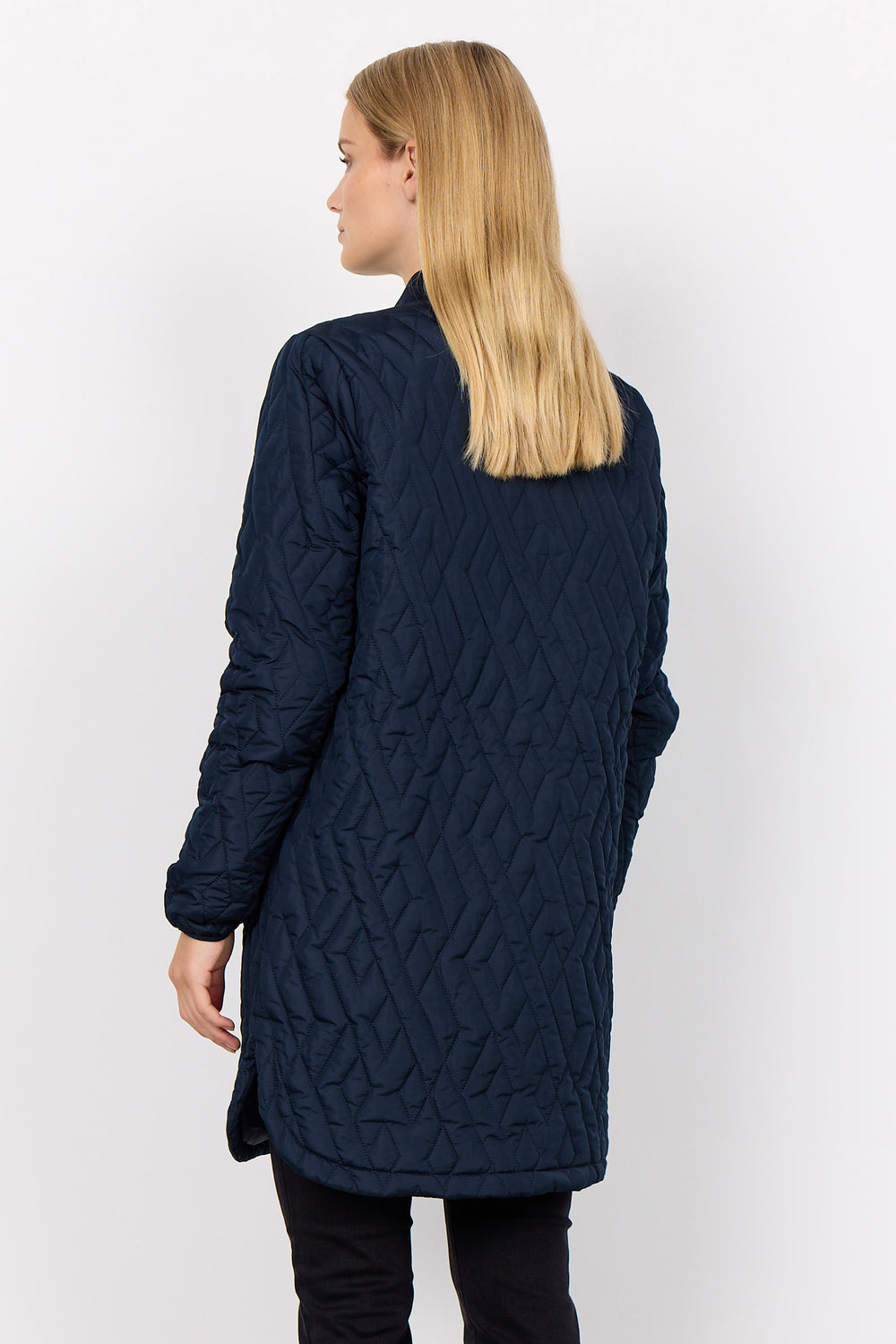 A woman with blonde hair is shown from the back wearing a dark navy blue quilted jacket against a plain white background.