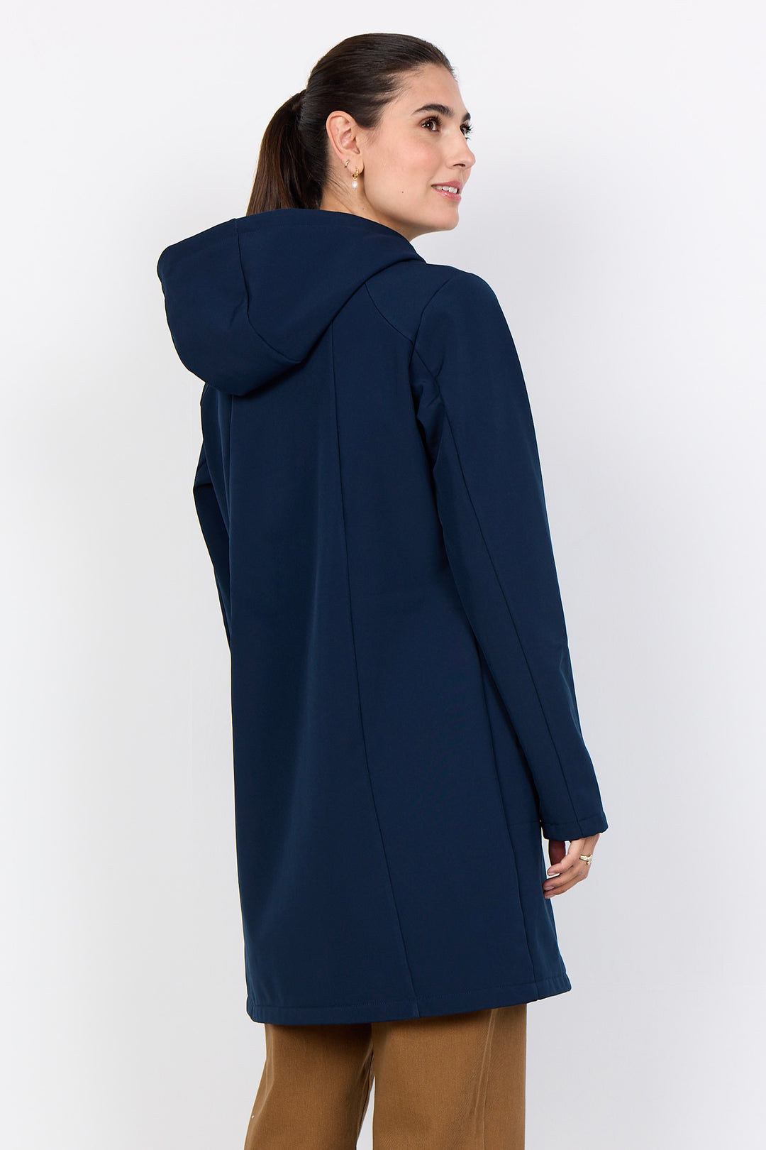A woman wearing a navy blue hooded coat, shown from a three-quarters back view against a plain light gray studio background.