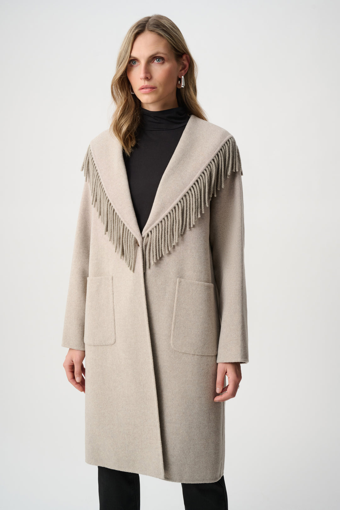 Woman wearing a beige coat with fringe details on a white background