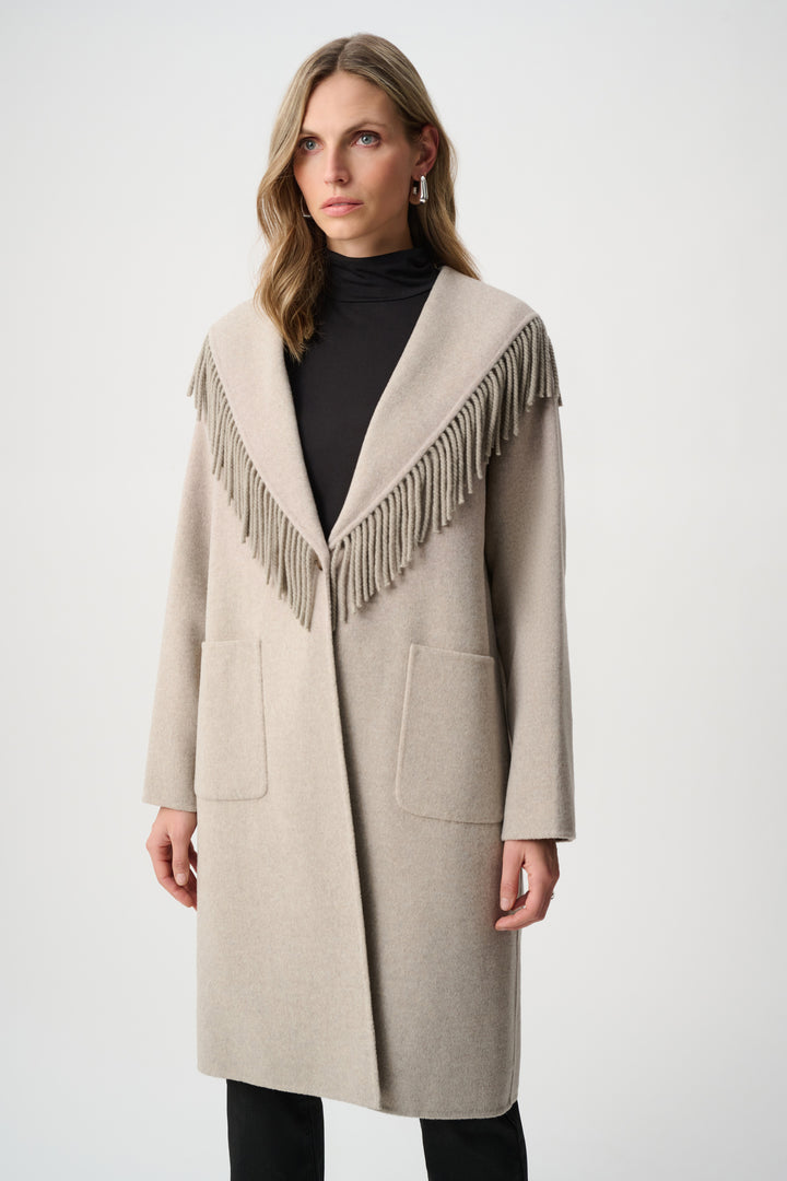 Woman wearing a beige coat with fringe details on a white background