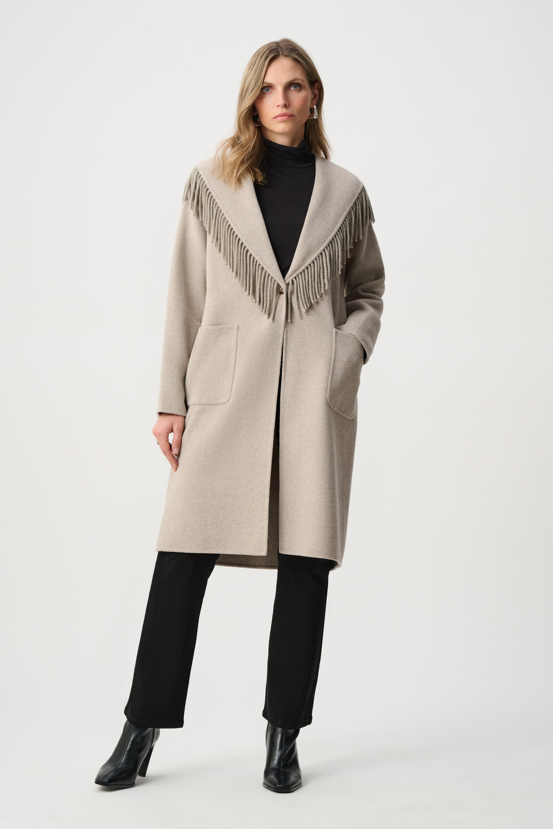 Woman wearing a beige coat with fringe details on a white background