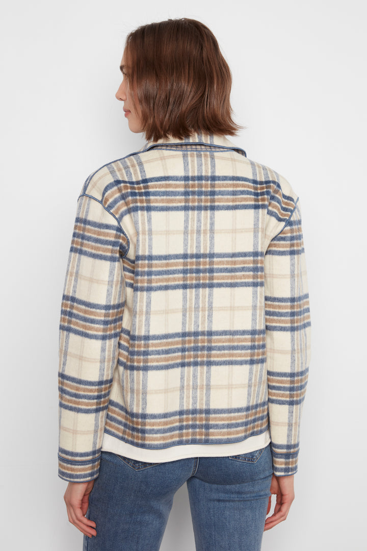 A woman shown from the back wearing a cream-colored plaid jacket with blue and brown stripes, paired with blue jeans, against a plain white background.