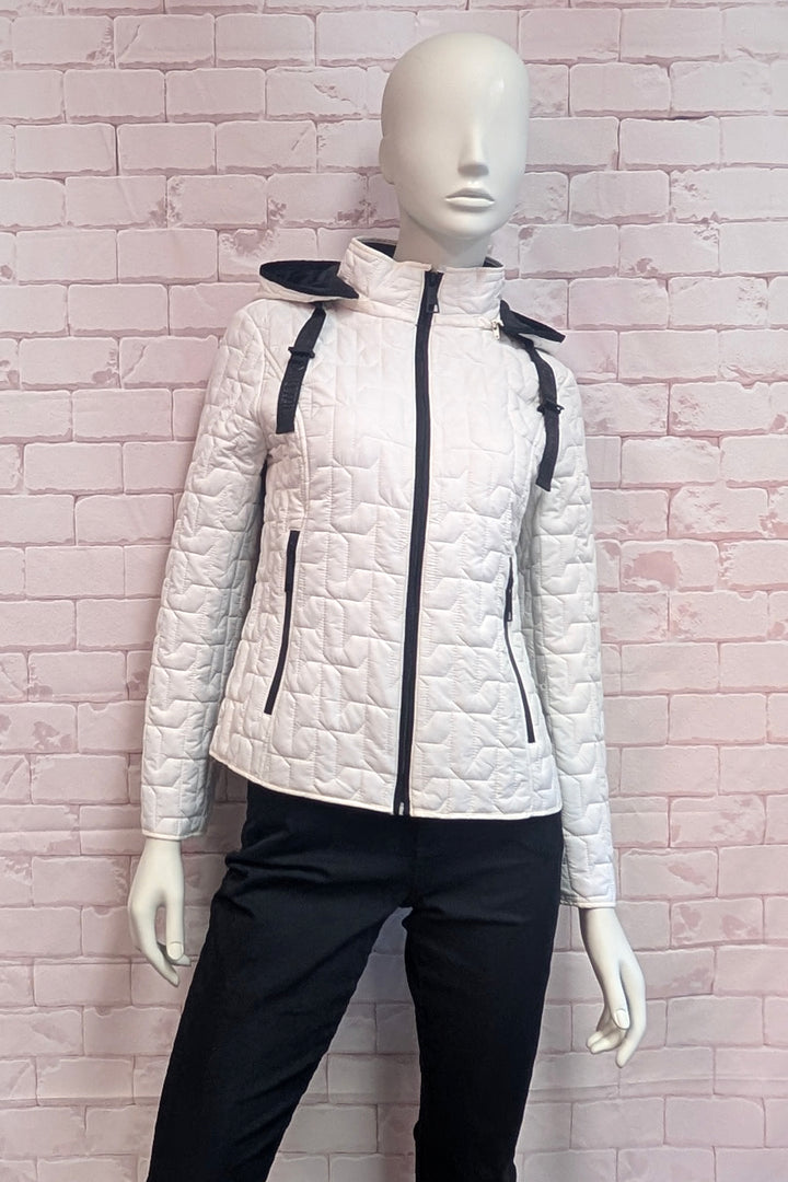 A white quilted hooded jacket with black zippers and trim, displayed on a white mannequin against a pink brick wall background.