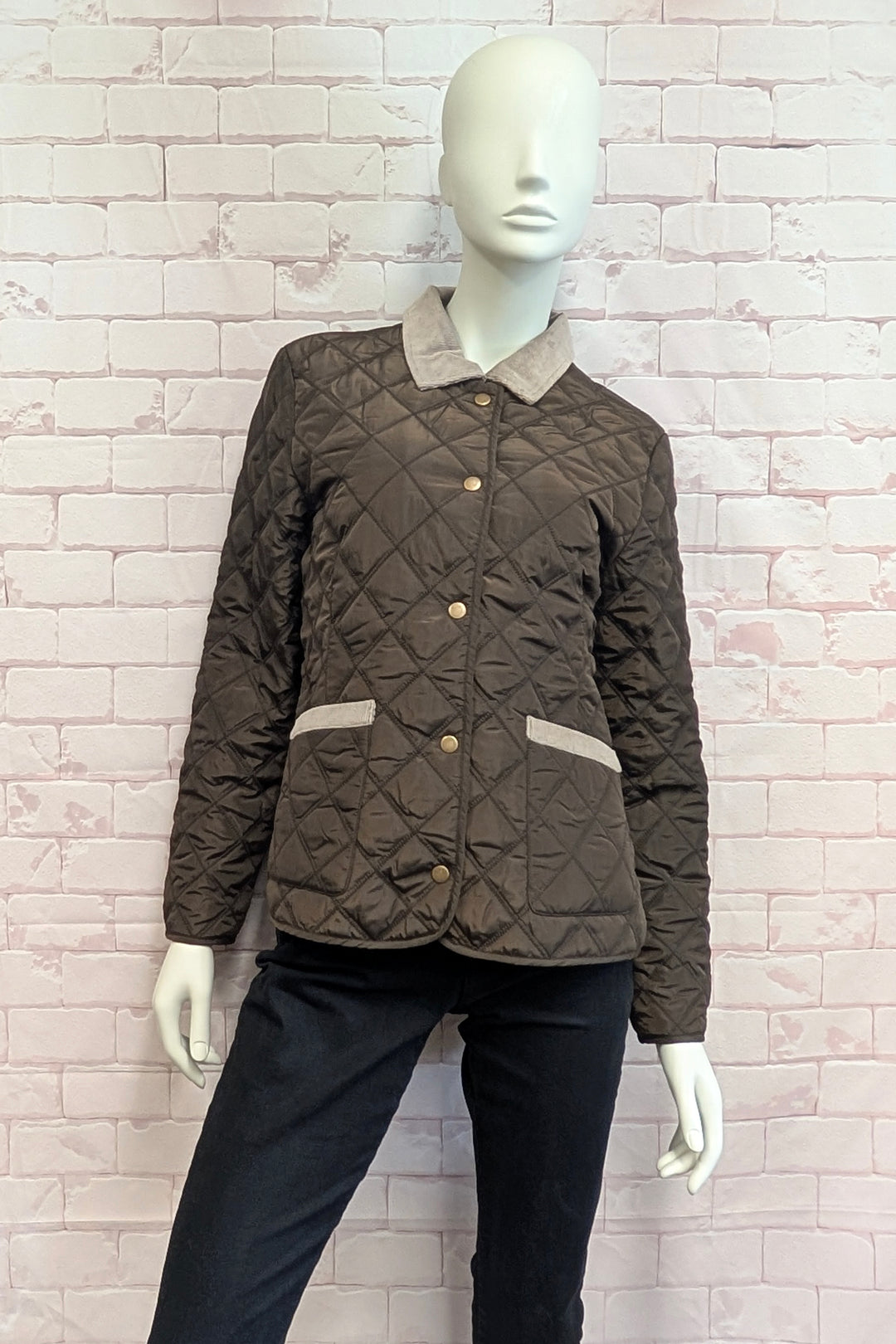 Mannequin wearing a quilted jacket in dark brown with a contrasting beige fleece collar and matching beige trim on the pockets, featuring gold-tone buttons.