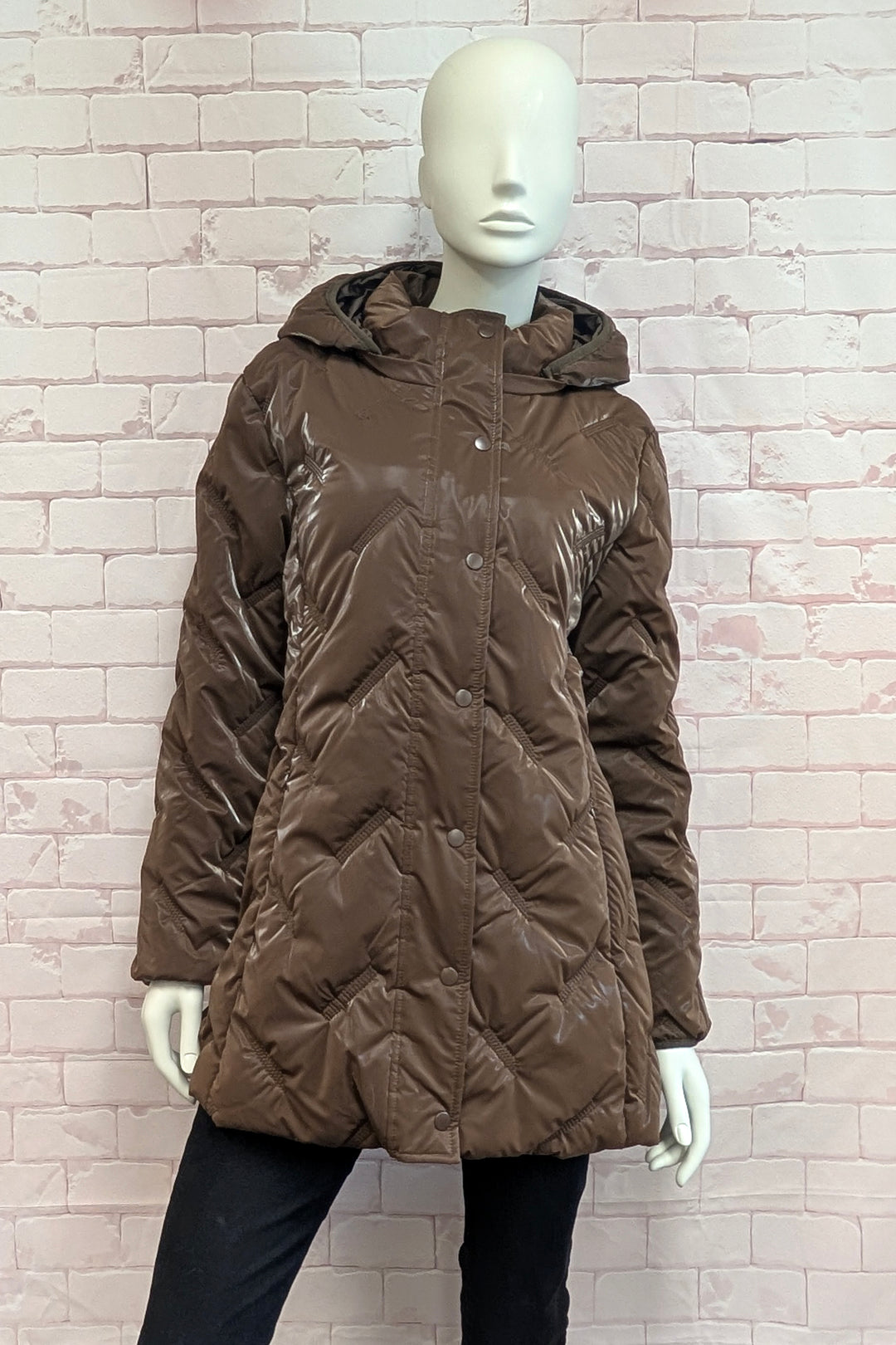 A mannequin wearing a An brown quilted hooded jacket with a snap-button front.