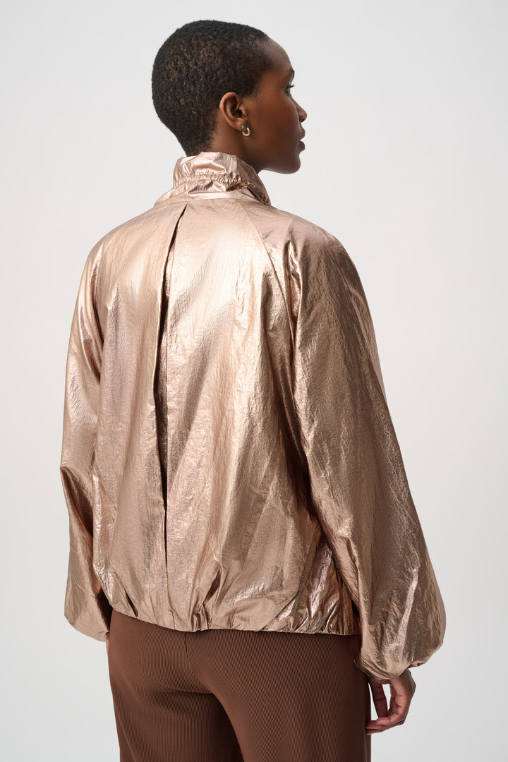 Woman modelling a rose gold jacket in front of a white background. 