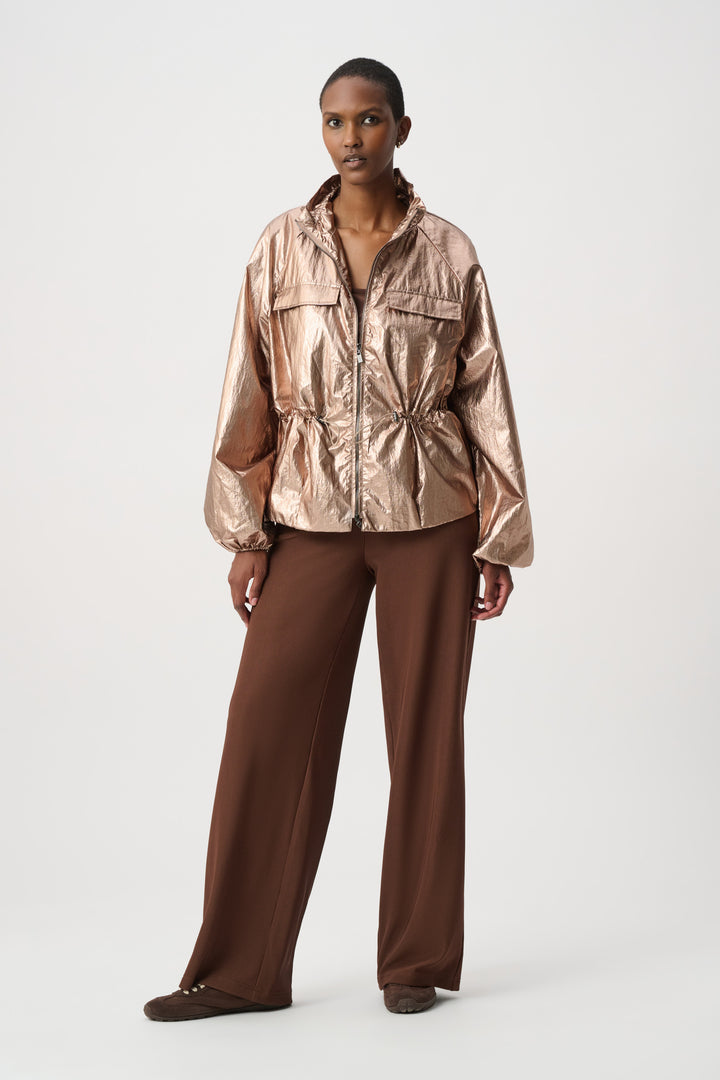 Woman modelling a rose gold jacket in front of a white background. 