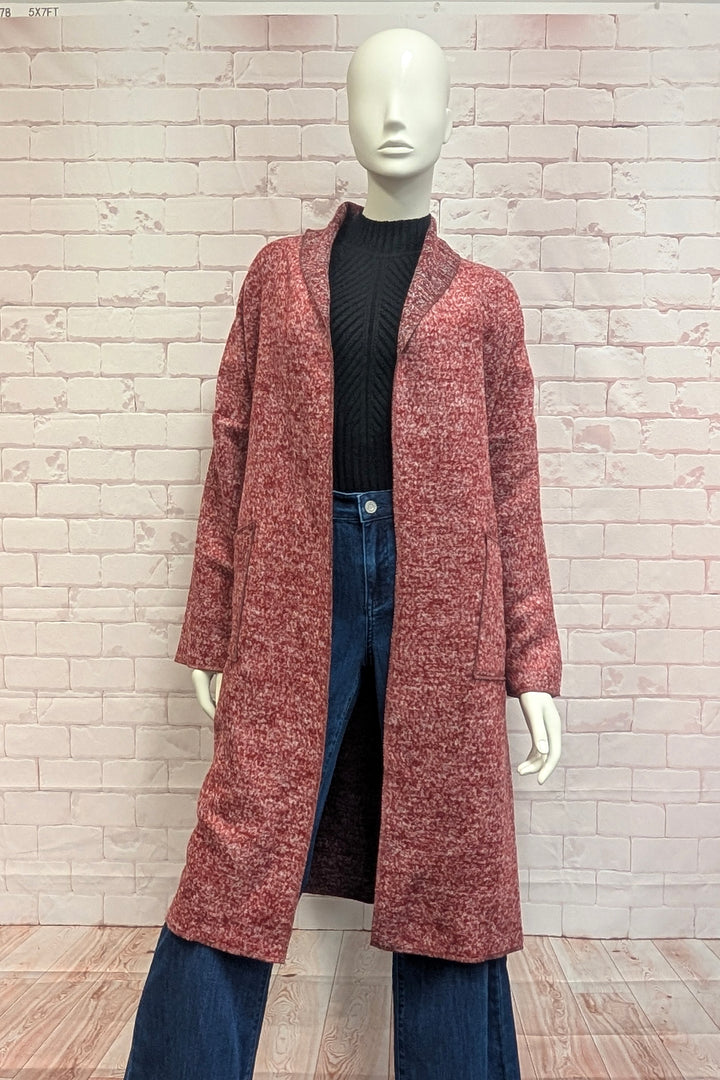 A mannequin modelling a boucle coat in front of a brick background. 