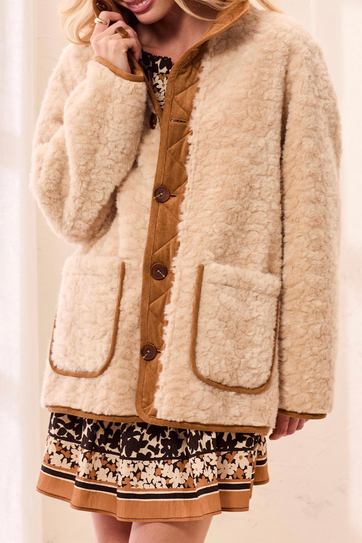 A woman wearing a reversible faux fur and sherpa jacket. 