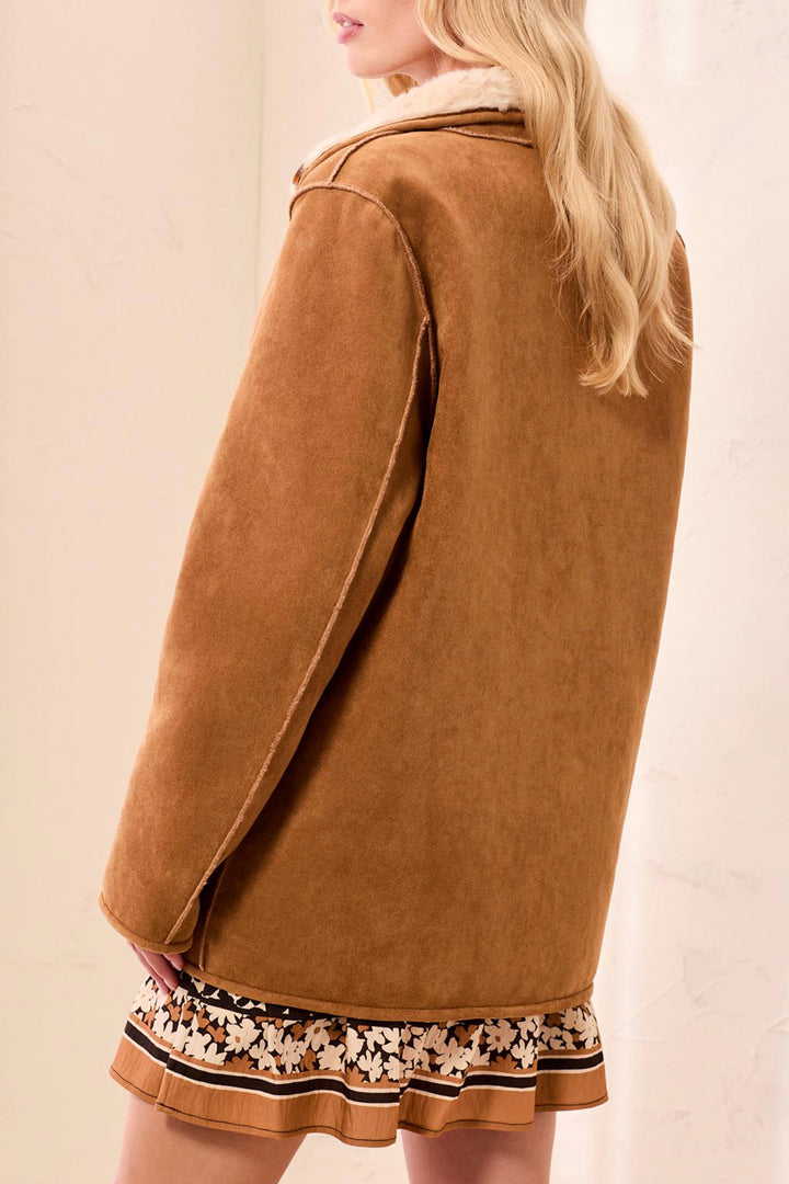 A woman shown from the back wearing a reversible faux fur and sherpa jacket. 