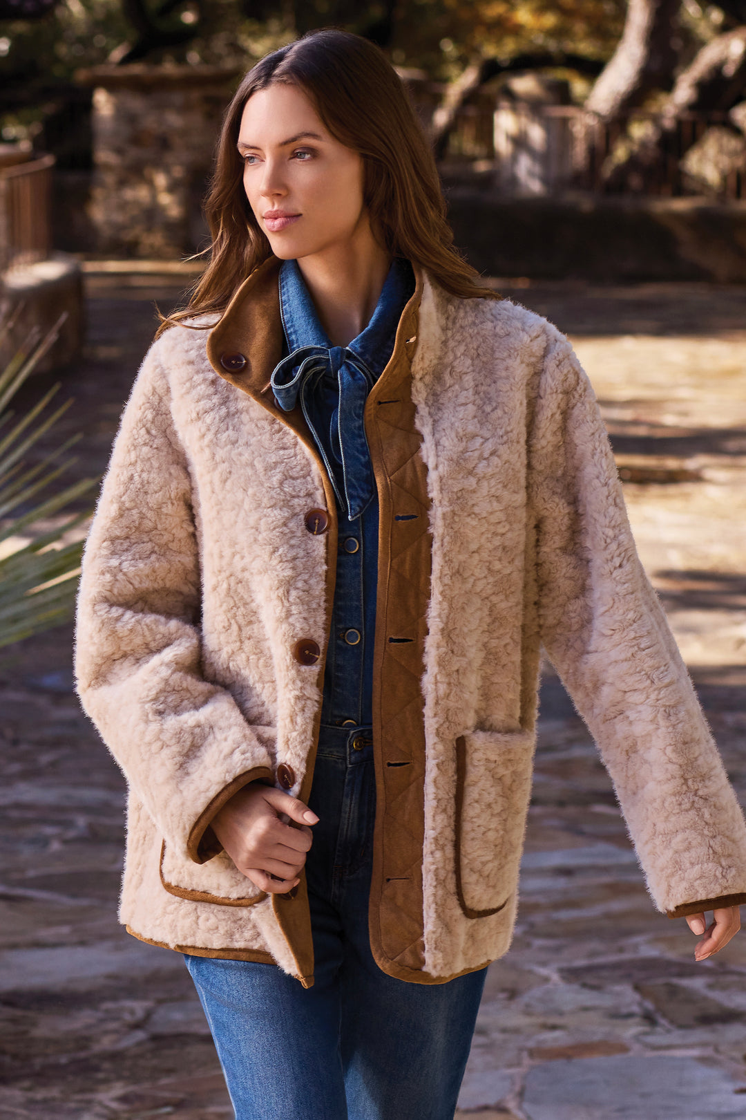 A woman wearing a reversible faux fur and sherpa jacket. 