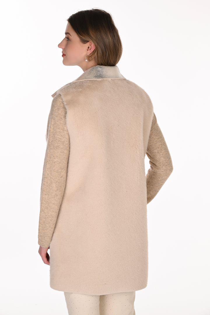 A woman shown from the back wearing a silver and cream long vest standing in front of a light grey background. 