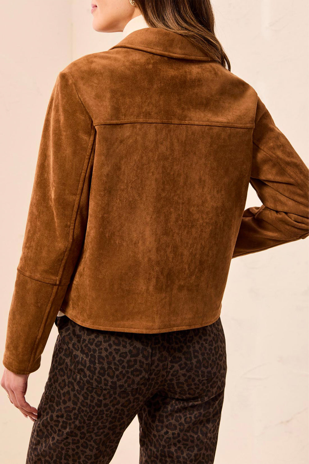 A woman shown from the back wearing a boxy faux suede jacket with large front pockets. 