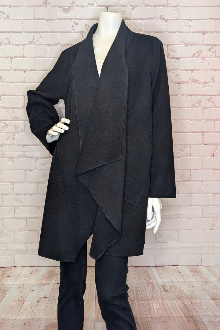 Black coat on a mannequin against a brick wall.