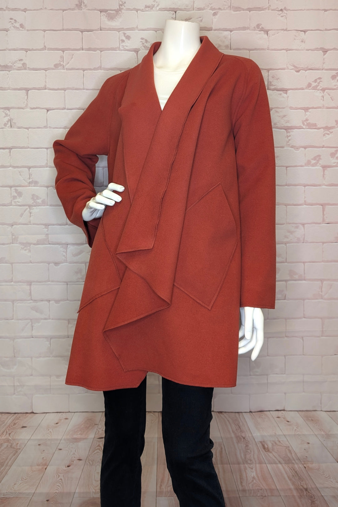 Brown coat on a mannequin against a brick wall.