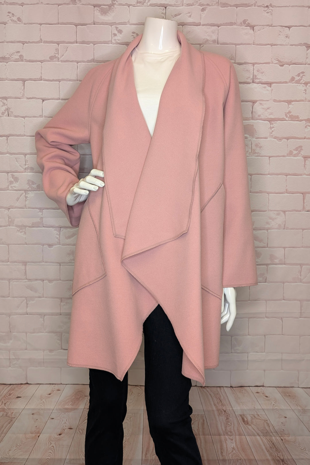 Pink coat on a mannequin against a brick wall.