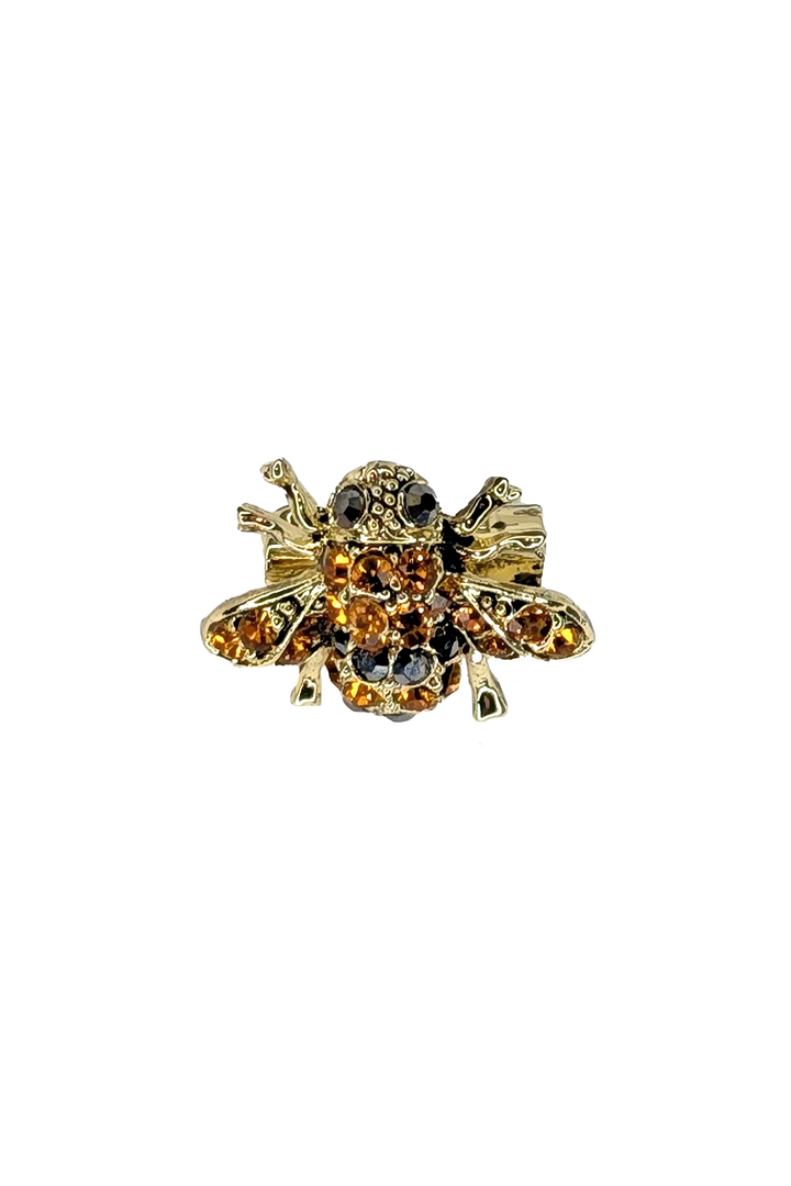 Gold bee-shaped brooch with gemstones on a white background