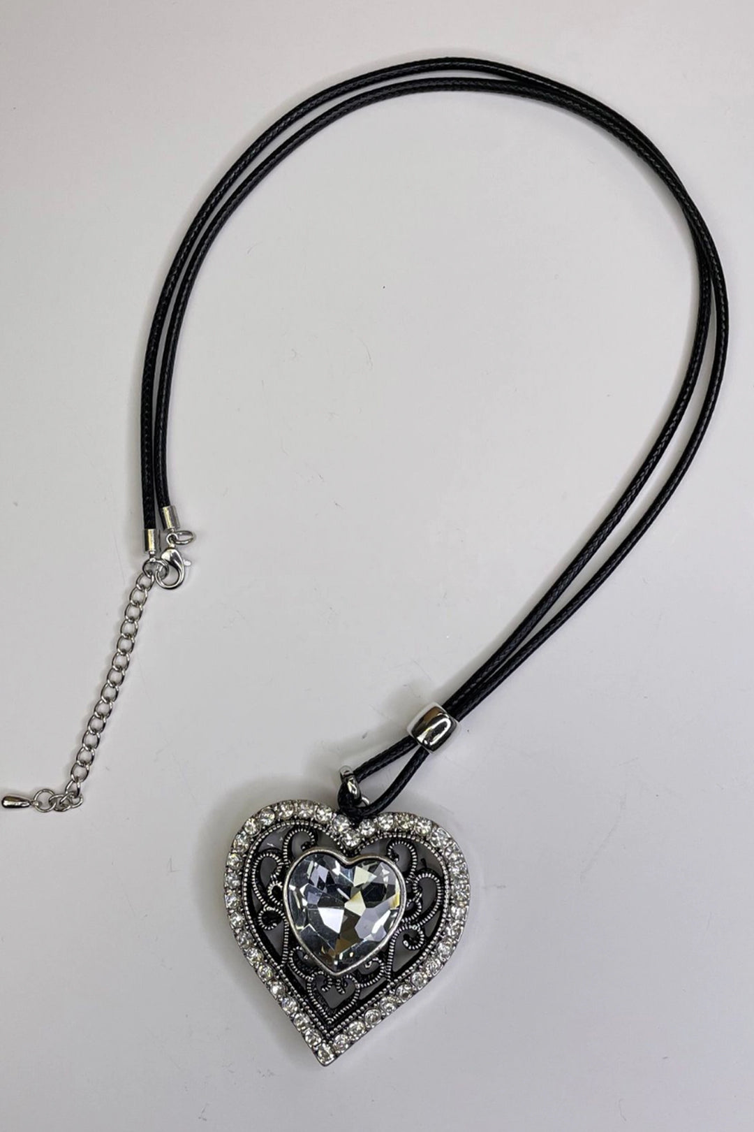 This elegant necklace features a dazzling heart-shaped rhinestone pendant with silver studs around the side.