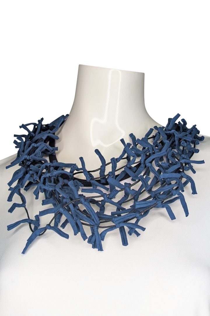 Blue textured necklace on a mannequin against a white background