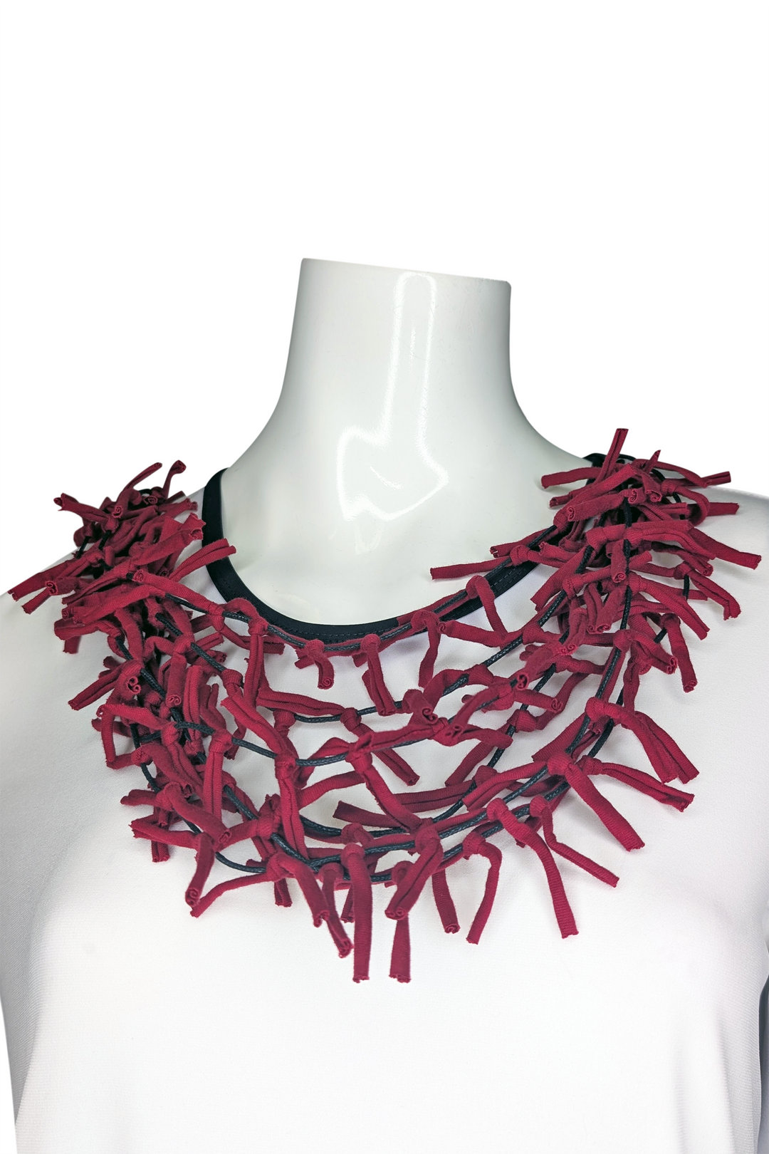 Red ribbon necklace on a mannequin against a white background