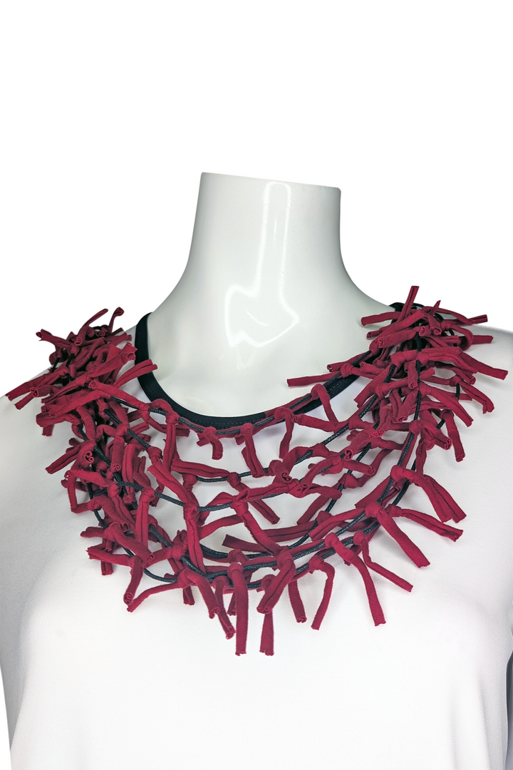 Red ribbon necklace on a mannequin against a white background