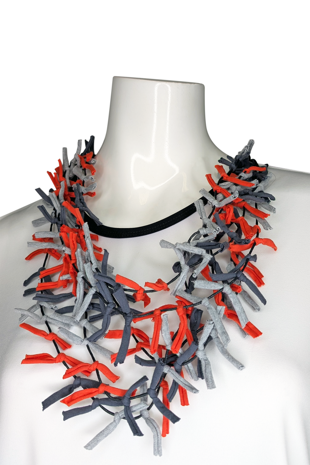 Necklace with red and gray ribbons on a mannequin against a white background