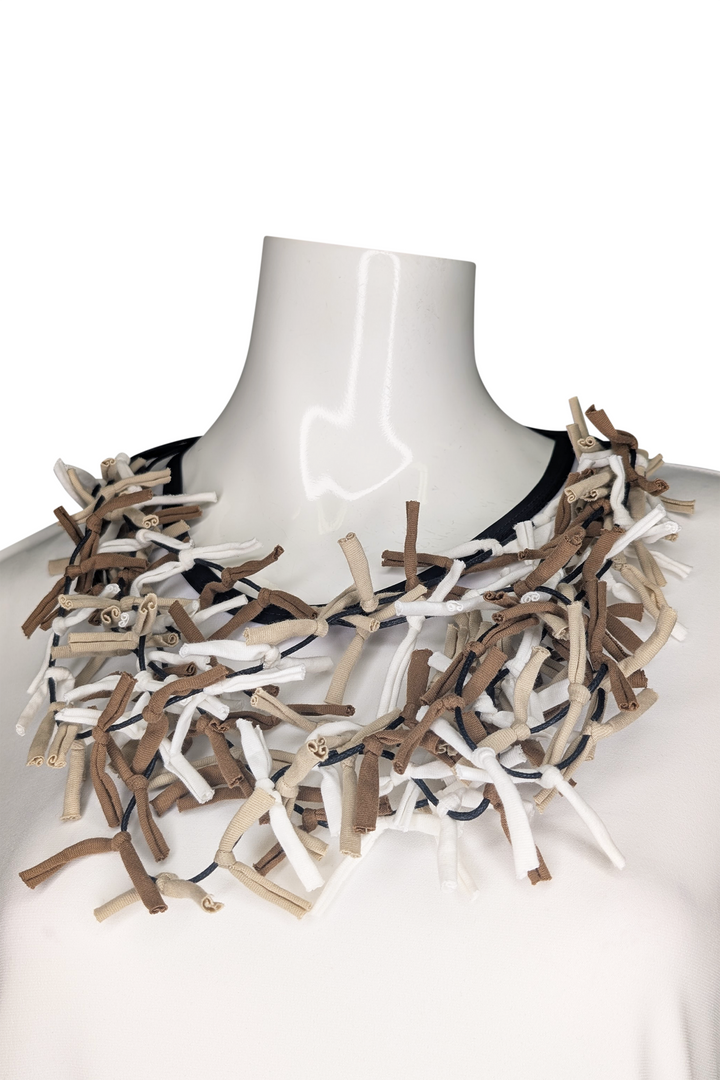 Textured necklace on a mannequin against a white background