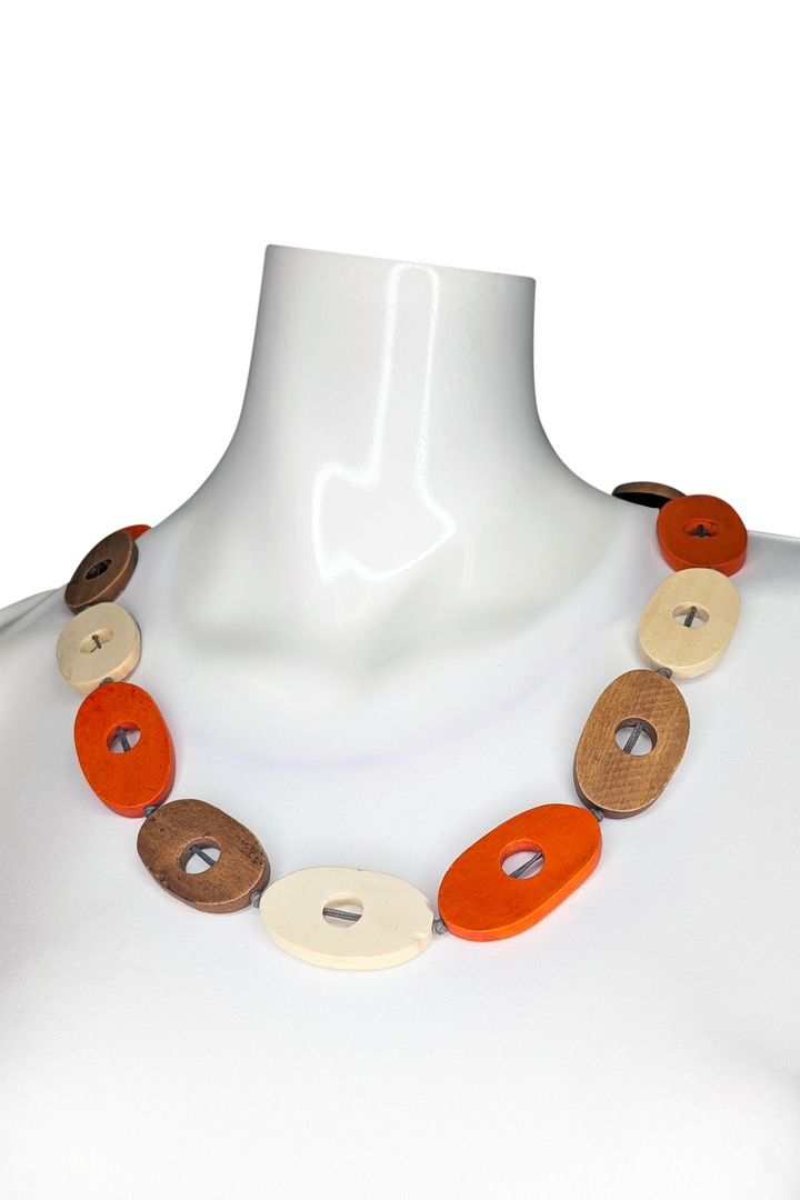 Necklace with circular wooden beads in orange colors on a mannequin.