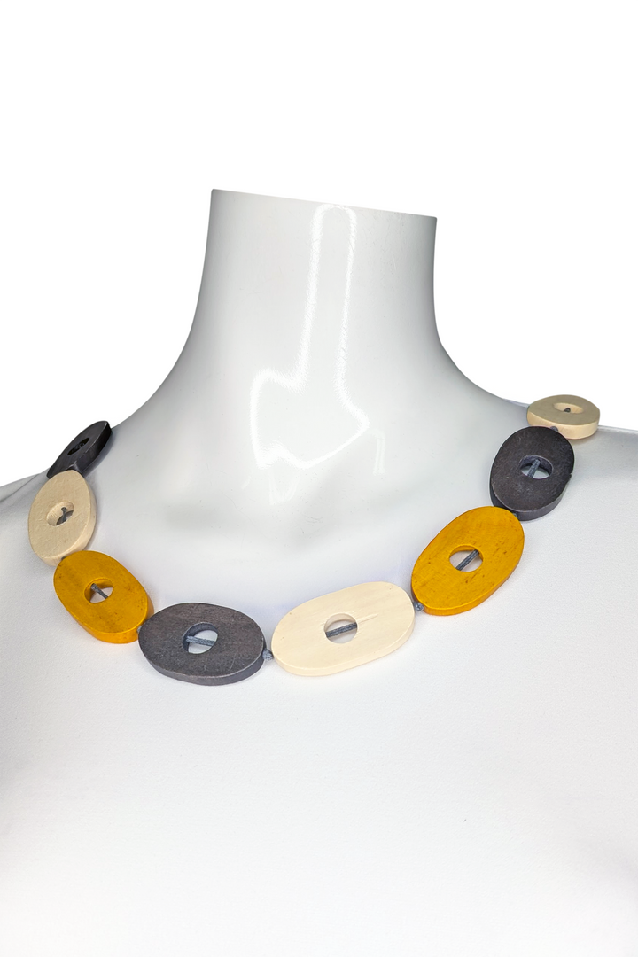 Necklace with colorful yellow circular beads on a white mannequin