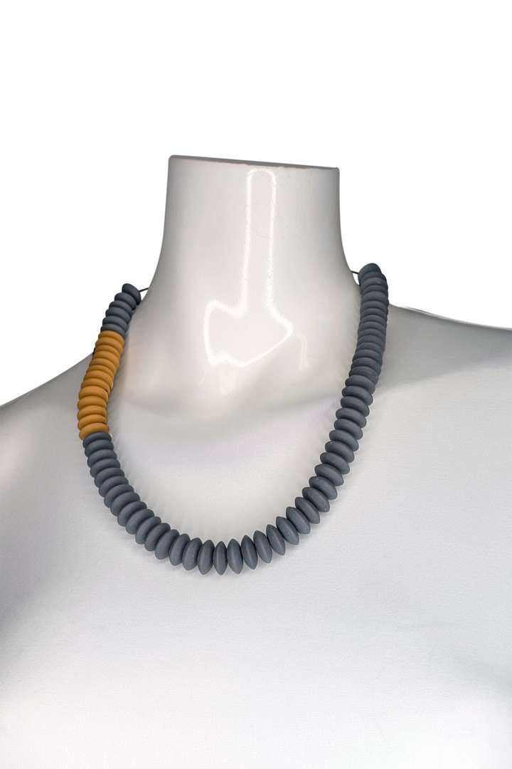 Necklace with gray and orange beads on a mannequin against a white background