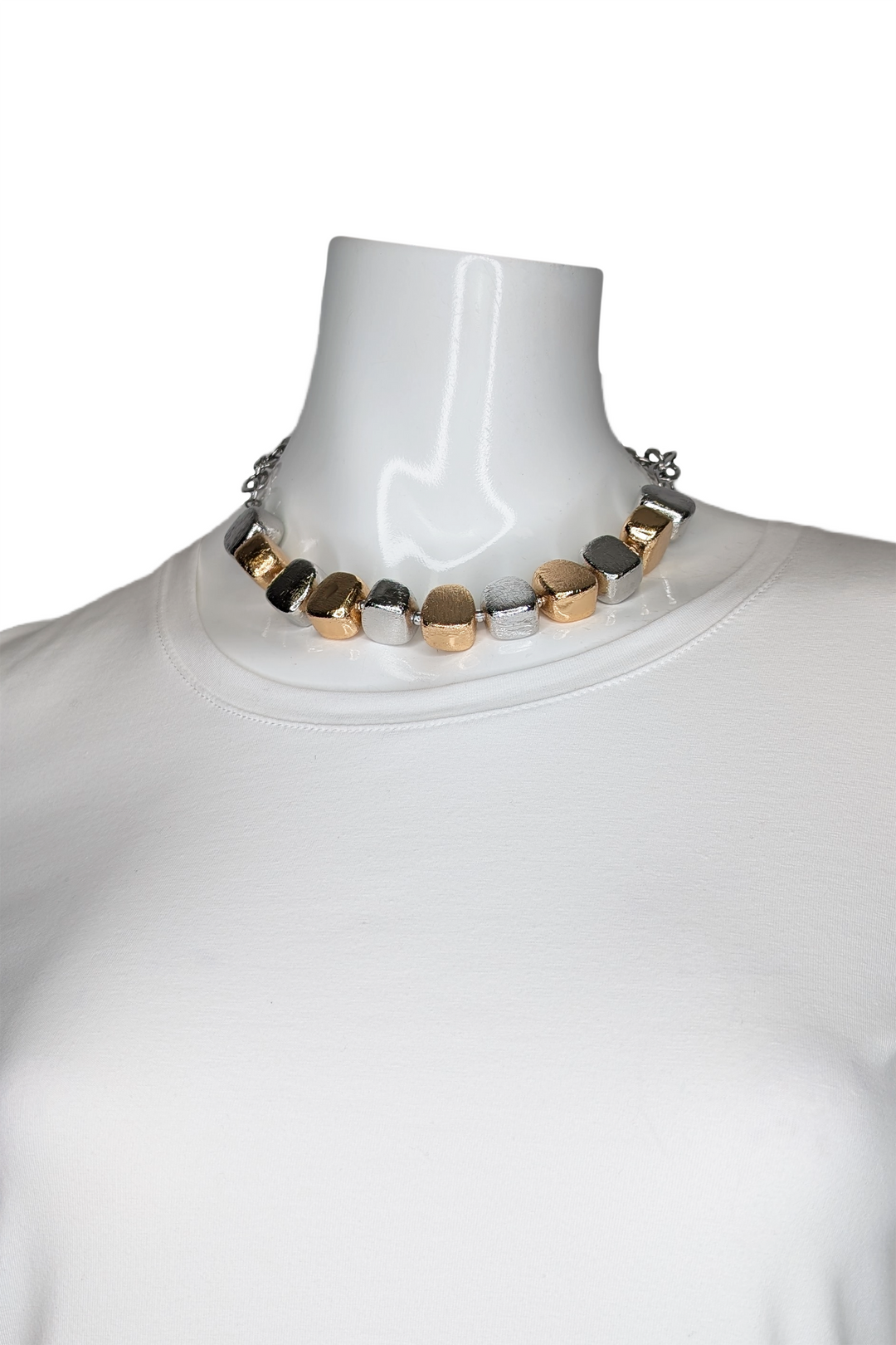 Mannequin wearing a necklace with gold and silver beads on a white background