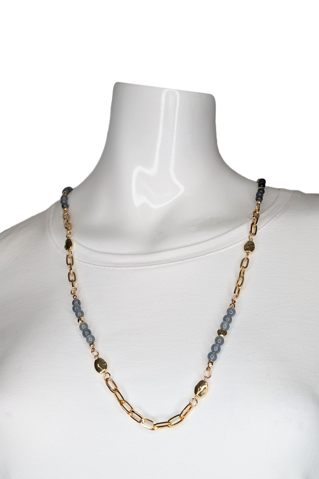 Necklace with gold chain and blue, grey beads on a mannequin against a white background