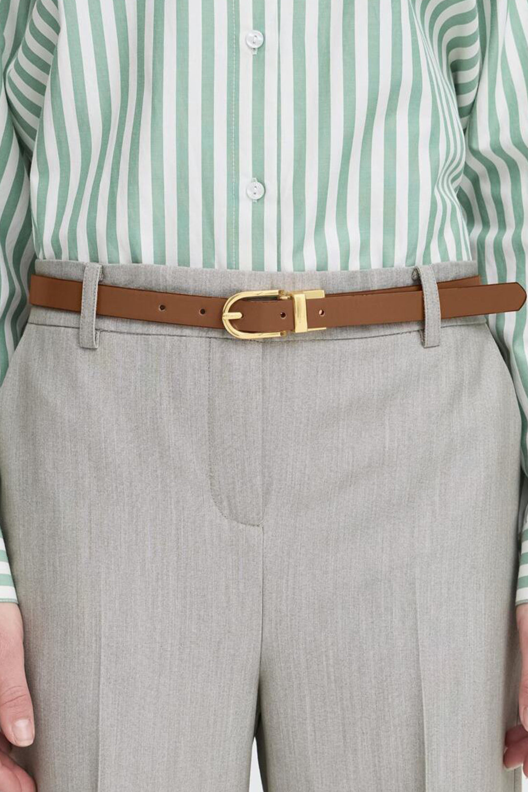Person wearing a green and white striped shirt, gray pants, and a brown belt with a gold buckle.