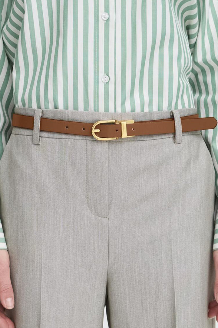 Person wearing a green and white striped shirt, gray pants, and a brown belt with a gold buckle.