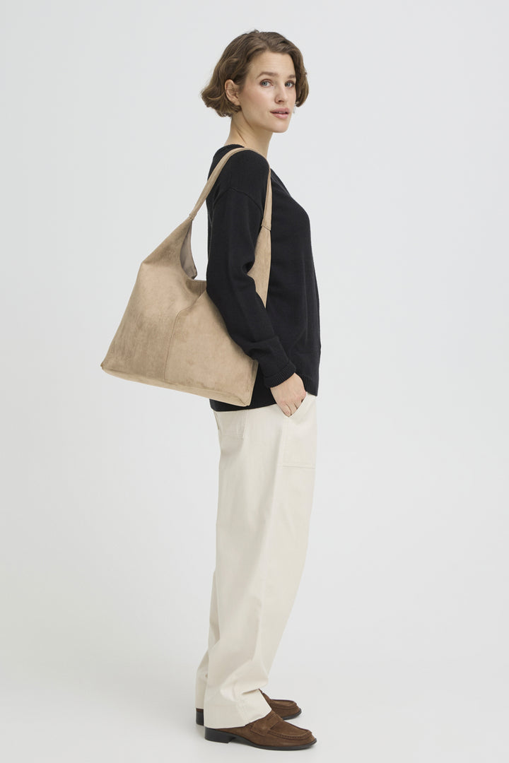 Woman holding a beige tote bag against a white background