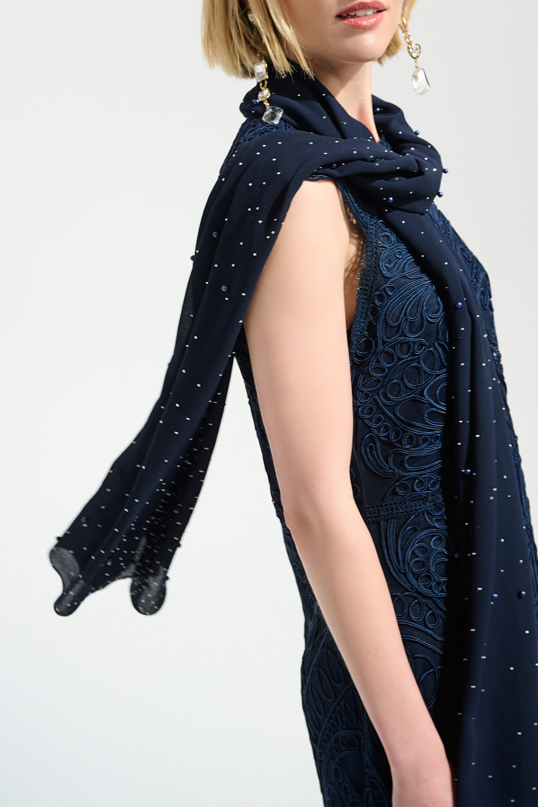 Navy blue scarf with  pearls and lace details draped over a person on a white background