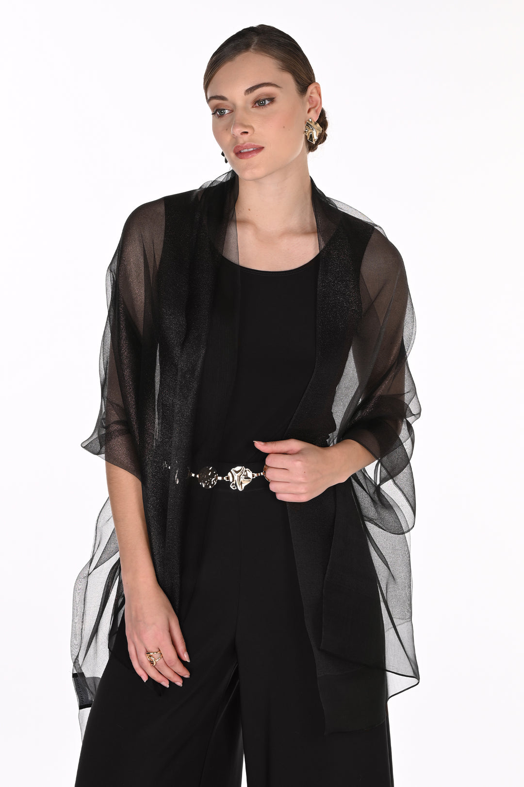 A woman modeling a sheer black mesh shawl draped over a black jumpsuit, photographed against a plain white studio background.