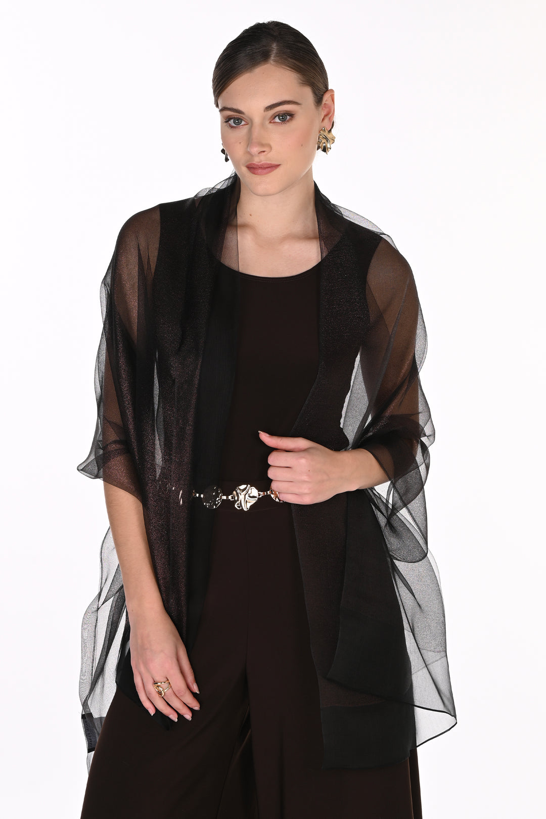 A woman modeling a black sheer mesh shawl draped over a black jumpsuit, set against a plain white studio background.
