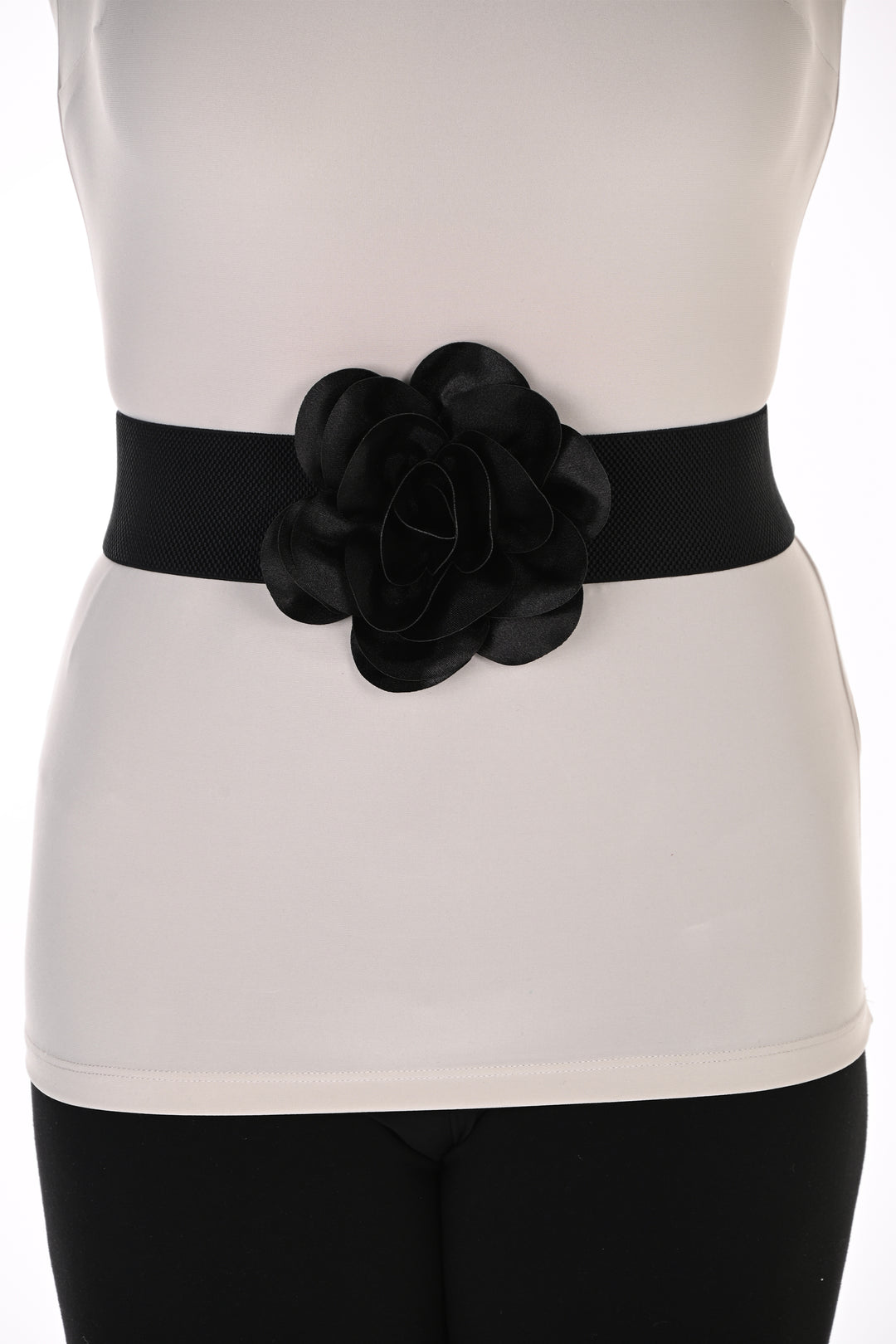 A black wide waist belt with a large layered fabric flower centerpiece, worn over a white sleeveless top and black leggings.