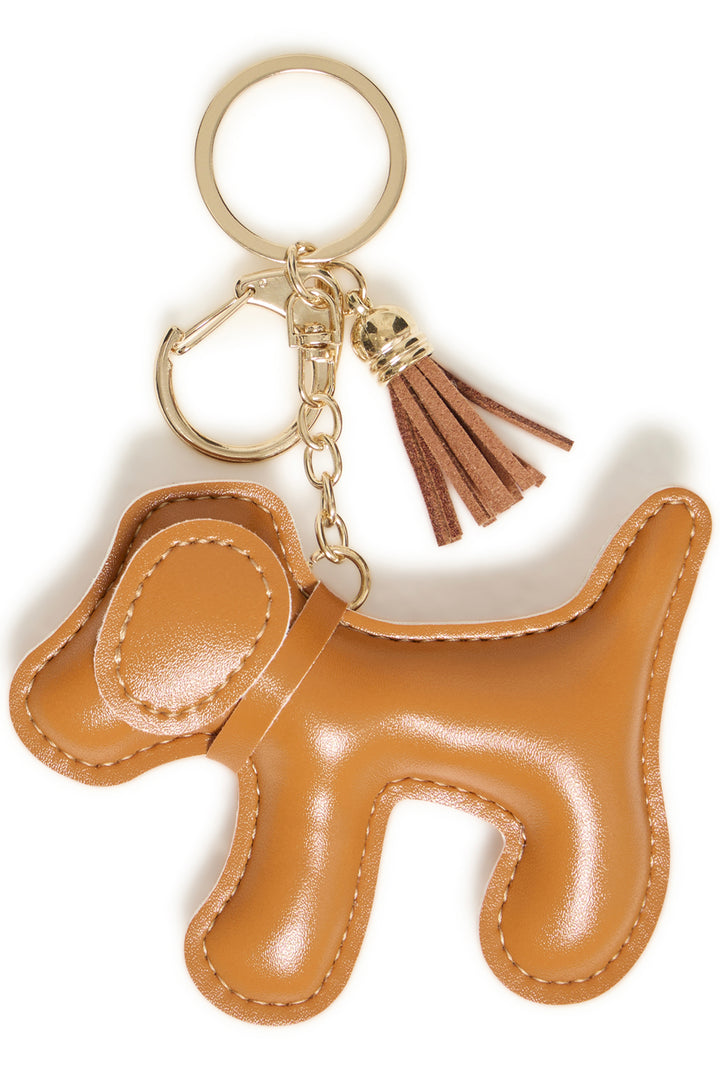 A tan leather dog-shaped keychain with gold-tone metal hardware and a matching leather tassel, shown on a plain white background.
