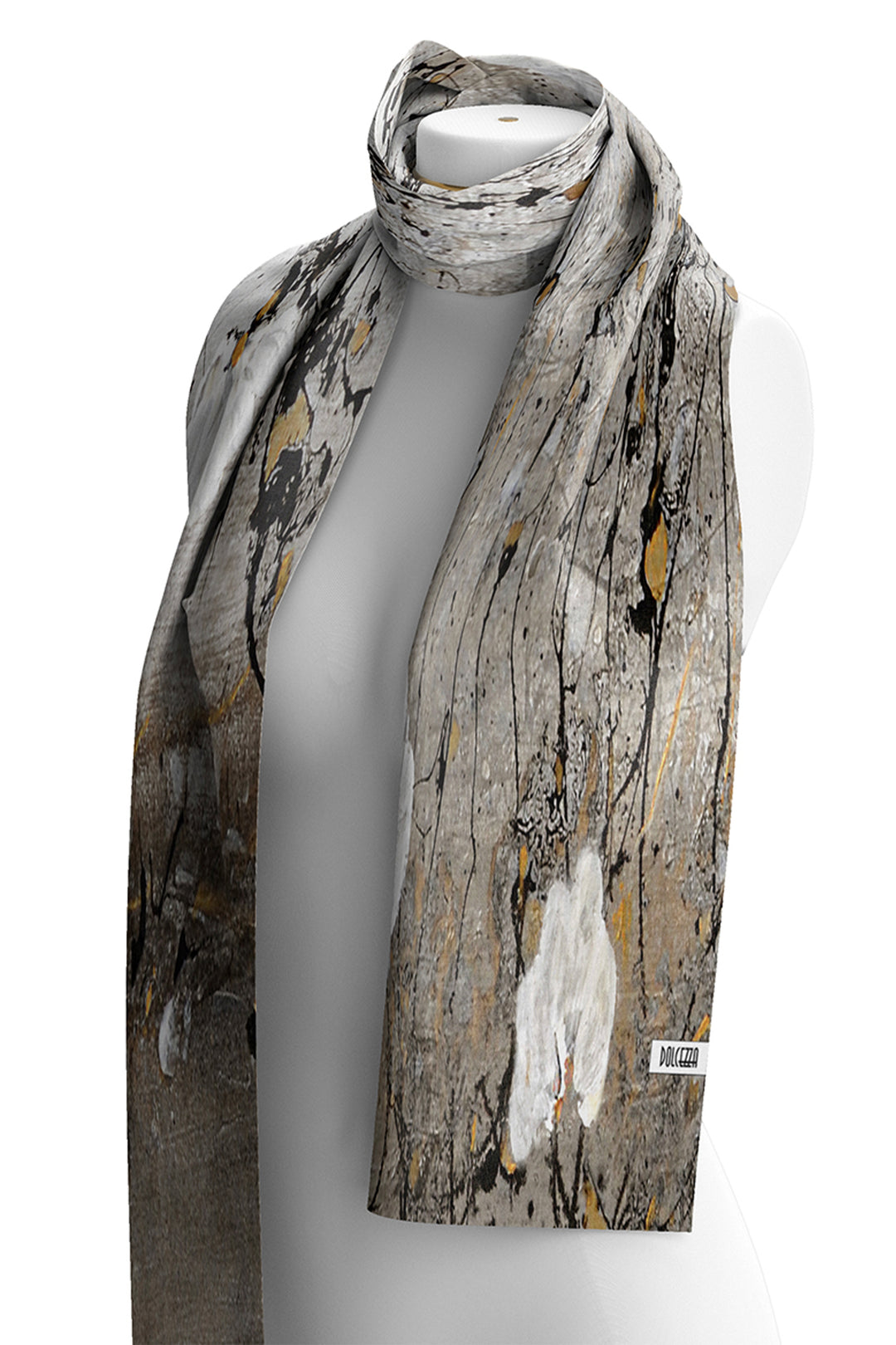 A lightweight scarf with an abstract bark-like print in gray, brown, black, and muted gold, draped on a white mannequin torso against a white background.